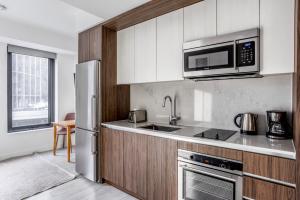 a kitchen with a refrigerator and a microwave at Seaport studio w fitness close to shops dining BOS-990 in Boston