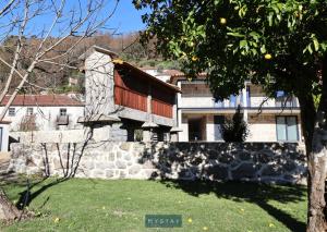 a house with a stone wall in a yard at MyStay - Casa d'Henrique in Vieira do Minho