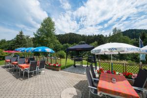 a patio with tables and chairs and umbrellas at Gruppenferienhaus Dressel in Warmensteinach