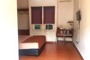 a bedroom with a bed and a table and two windows at Aryani Suites Syariah in Jakarta