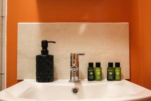 een wastafel in de badkamer met een fles zeep en een zeepdispenser bij Studio-Sleeps 4-10 min H Potter-17 Min London in Watford