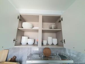 a kitchen cabinet filled with white bowls and plates at P house in Seoul