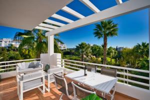 a balcony with a table and chairs and palm trees at Al-411 Estepona - Apartment - Alcazaba Lagoon in Estepona