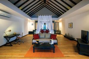 sala de estar con sofá y mesa en Atmosphere Kanifushi - Premium All Inclusive with Free Transfers, en Lhaviyani Atoll