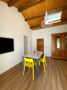 a dining room with a table and two yellow chairs at Levante Flat - 100 m from the beach in Fano