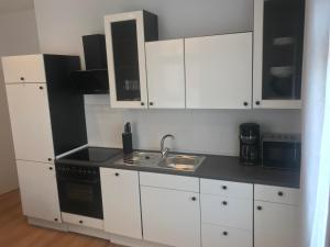 eine Küche mit weißen Schränken und einem Waschbecken in der Unterkunft Mimalou Apartment in Zwickau in Zwickau
