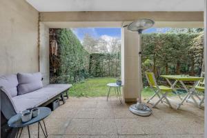 eine Terrasse mit einem Sofa, einem Tisch und einem Tisch in der Unterkunft Le Cocon du Cœur de Ville in Le Plessis-Robinson