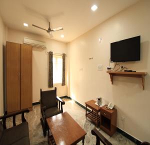 a living room with a table and a flat screen tv at Hotel Rathnavel Towers in Chennai