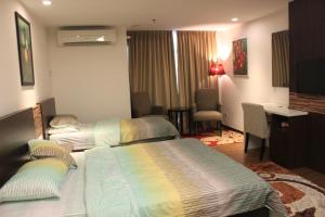 a hotel room with two beds and a desk at Adha Studio & Suite Kota Bharu in Kota Bharu