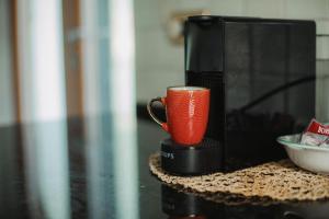 una tazza di caffè rosso seduta sopra un forno a microonde di Neblou ad Aosta