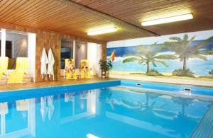 a large swimming pool with a mural of palm trees at Landhotel Haagerhof in Aigen im Mühlkreis