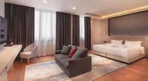 um quarto com uma cama, um sofá e uma cadeira em FUHOTEL em Bukit Mertajam