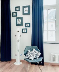 a blue chair in a room with pictures on the wall at High Level Apartment in Mannheim