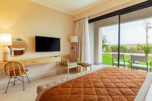 a bedroom with a large bed with a television and sliding glass doors at Jaz Amara in Marsa Alam City