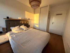een slaapkamer met een groot bed met witte lakens en kussens bij Location for Olympic Games (JO) in Houilles