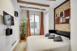 een slaapkamer met een wit bed en een bakstenen muur bij Bastille - Gare de Lyon - Appartement familial in Parijs