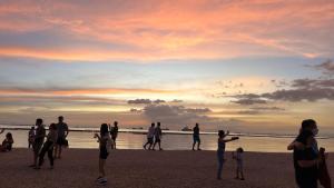 a group of people standing on the beach at sunset at Mall of Asia Shore 2 Condo in Manila