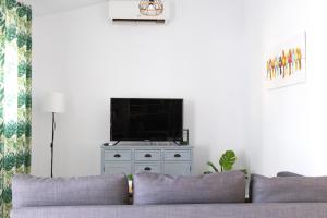 een woonkamer met een bank en een flatscreen-tv bij Villa ANDROMEDA in Chiclana de la Frontera