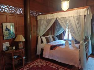 1 dormitorio con cama con dosel y ventana en Ayutthaya teak home Homestay, en Phra Nakhon Si Ayutthaya
