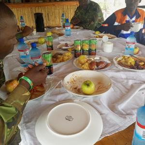 un grupo de personas sentadas en una mesa con comida en Mokoka Rest Camp, en Nata