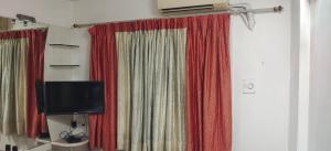 a room with red curtains and a tv at P N A Apartments in Kālva