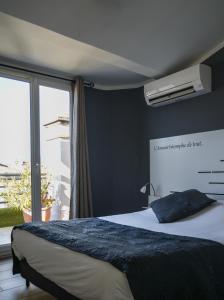 a bedroom with a bed and a large window at Celenya Hôtel in Toulon