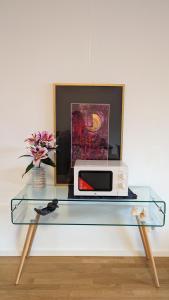 a glass table with a microwave and a painting at Luxury, Spacious, Sunny home in the heart of Berlin in Berlin