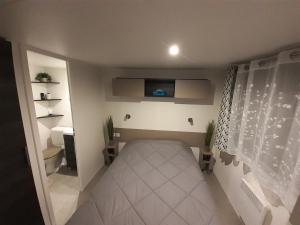 Habitación pequeña con cama y TV. en mobile home for you Les Rives de Condrieu, en Condrieu