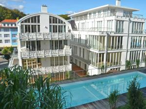 an apartment building with a swimming pool in front of it at Villa "Johanna" Sellin - WG11 mit Kamin und großer Terrasse in Ostseebad Sellin