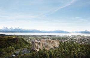 a building on a hill with a lake and mountains at Wood Hotel Bodø in Bodø