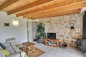 uma sala de estar com um sofá e uma parede de pedra em La Clef des Champs, gîte à la ferme au pied des vignes, Finistère sud ! em Pouldergat
