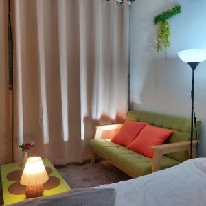 sala de estar con sofá verde y lámpara en With us house en Ansan