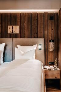 een slaapkamer met een wit bed en een houten muur bij Werdenfelserei in Garmisch-Partenkirchen