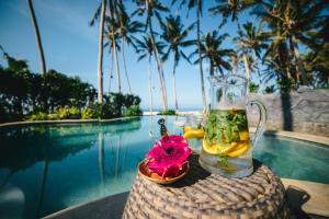 a drink on top of a table next to a pool at Beachfront Villa Laut Tabanan in Tabanan