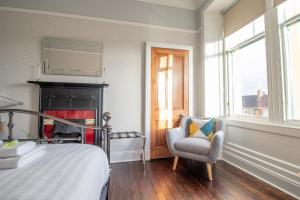 ein Schlafzimmer mit einem Bett, einem Stuhl und einem Kamin in der Unterkunft Pass the Keys Beautiful, traditional 2 bed flat w free parking in Glasgow