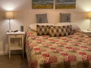 a bedroom with a bed with a quilt and two lamps at Morgraig in Cardiff