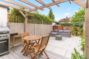 a patio with a wooden pergola and a table and chairs at Little Braybrooke Cottage- Saffron Walden in Saffron Walden