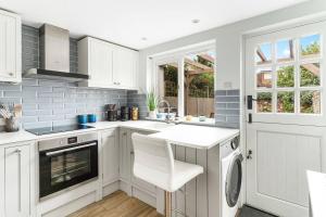 a kitchen with white cabinets and a dishwasher at Little Braybrooke Cottage- Saffron Walden in Saffron Walden