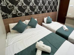 クアンタンにあるKUANTAN BESERAH BUDGET HOTELのベッドルーム1室(ベッド2台、緑と白の枕付)