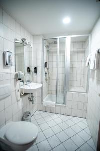 a bathroom with a shower and a toilet and a sink at Hotel am Schillerplatz in Pleidelsheim