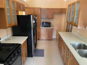 a kitchen with wooden cabinets and a black refrigerator at Oasis @ Richmond Estate - Ocho Rios - St Ann in Richmond