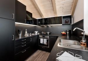 una cocina con armarios negros y fregadero en Am Dorfbrunnen, en Oetz