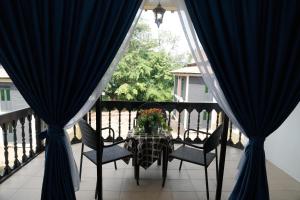 a table and chairs on a balcony with blue curtains at Putera Island Resort in Malacca