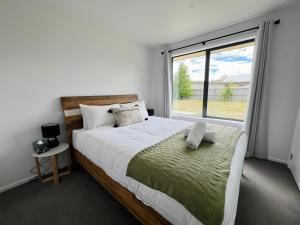 a bedroom with a large bed and a large window at Leisure Holiday Home Lake Hayes Easte Queenstown in Arrowtown
