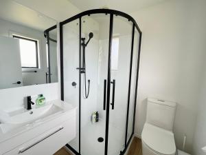 a bathroom with a shower and a toilet and a sink at Leisure Holiday Home Lake Hayes Easte Queenstown in Arrowtown