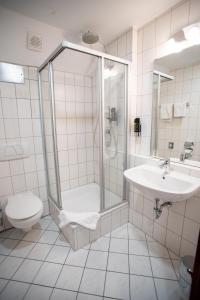 a bathroom with a shower and a toilet and a sink at Hotel am Schillerplatz in Pleidelsheim