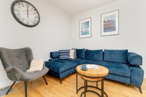 sala de estar con sofá azul y reloj en Gdynia Port Marine Apartment with Sea View by Renters en Gdynia