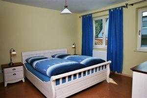 a bed in a bedroom with blue curtains and a window at Ferienwohnung „Rosarium“ in Gunzenhausen