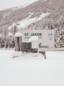 a sign for the st jago inn in the snow at AURA Bed & Breakfast in Sankt Jakob in Defereggen