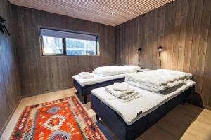 two beds in a room with a window and a rug at Stor moderne leilighet i Henningsvær, 70 kvm in Henningsvær